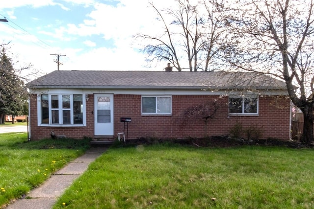 view of front of house with a chimney, brick siding, entry steps, and a front yard