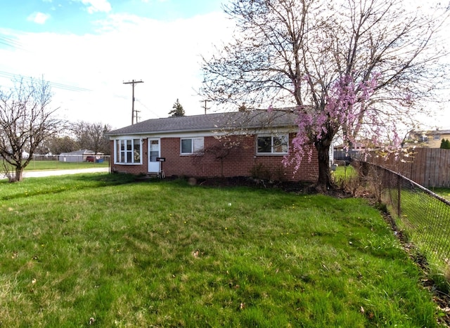 view of front of house featuring brick siding, a front yard, and fence