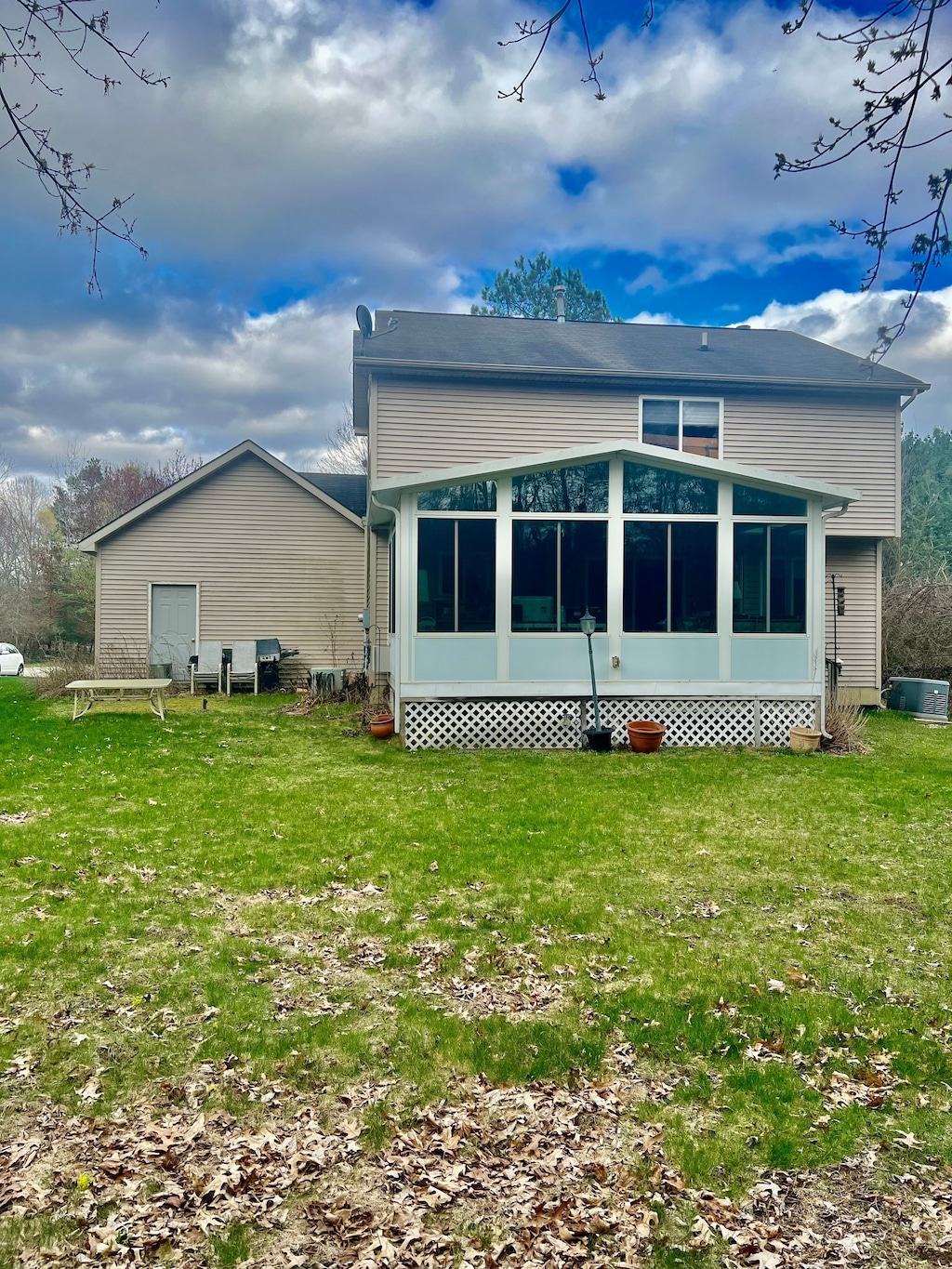 rear view of property with a sunroom and a lawn