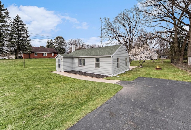 exterior space with a lawn, a shingled roof, and a chimney