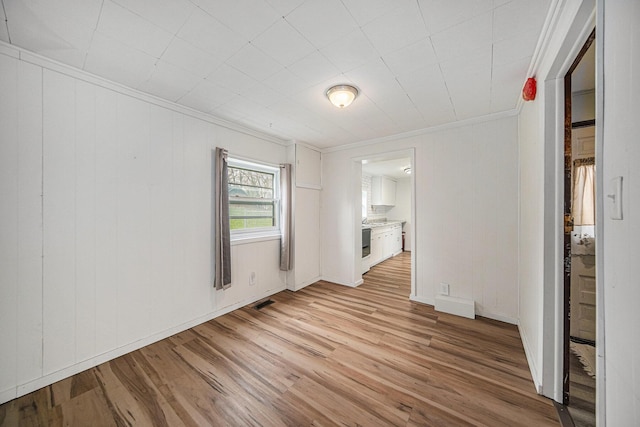 empty room featuring crown molding, visible vents, and light wood-style flooring