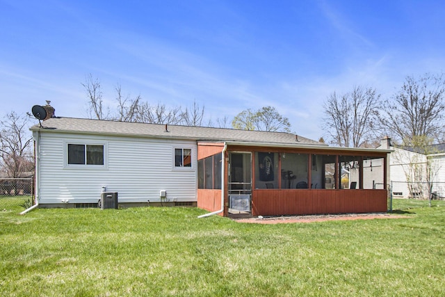 rear view of house featuring fence, a sunroom, a yard, and central AC unit
