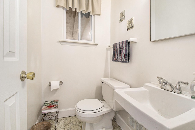 half bathroom with baseboards, a sink, and toilet