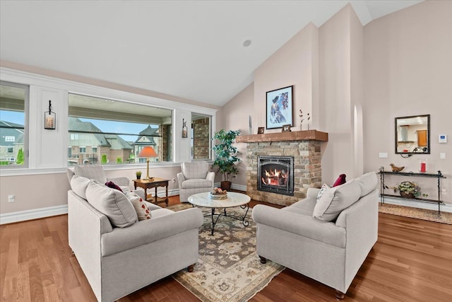 8427 Boulder Shores Dr, South Lyon, MI 48178 - living room featuring high vaulted ceiling, wood finished floors, a stone fireplace, healthy amount of natural light, and baseboards