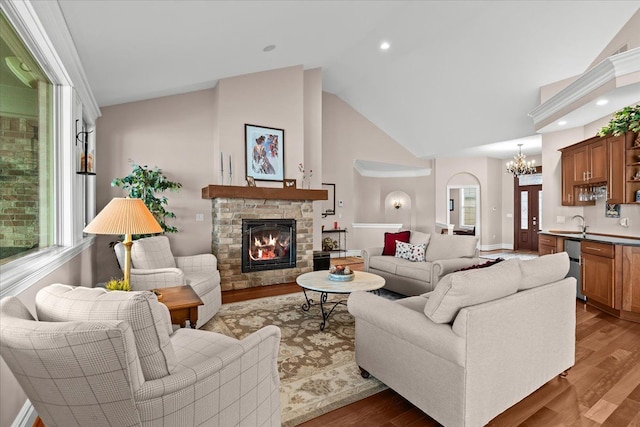 8427 Boulder Shores Dr, South Lyon, MI 48178 - living room featuring wood finished floors, a stone fireplace, healthy amount of natural light, a chandelier, and high vaulted ceiling