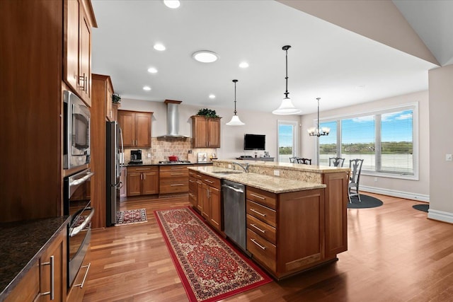 8427 Boulder Shores Dr, South Lyon, MI 48178 - kitchen with wall chimney range hood, stainless steel appliances, brown cabinets, wood finished floors, and decorative backsplash