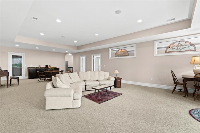 8427 Boulder Shores Dr, South Lyon, MI 48178 - living room featuring carpet flooring, recessed lighting, a tray ceiling, arched walkways, and baseboards