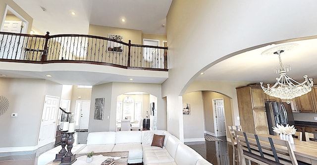 living room featuring recessed lighting, a high ceiling, a chandelier, baseboards, and arched walkways