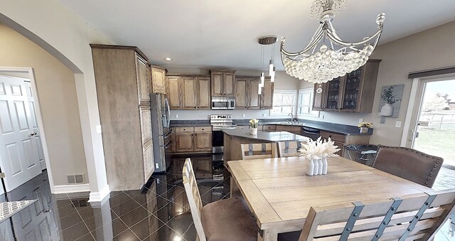 dining area featuring arched walkways, an inviting chandelier, granite finish floor, baseboards, and visible vents