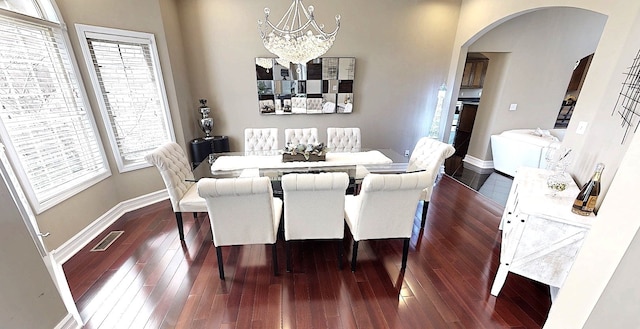 dining area featuring a chandelier, visible vents, arched walkways, and plenty of natural light