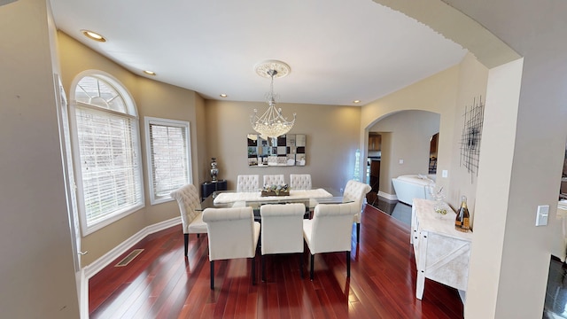 dining area featuring visible vents, baseboards, an inviting chandelier, dark wood-style flooring, and arched walkways