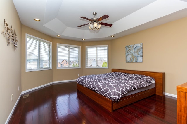 bedroom with wood finished floors, a raised ceiling, and baseboards