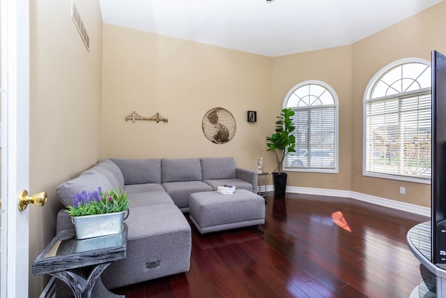 living room with hardwood / wood-style floors, visible vents, and baseboards