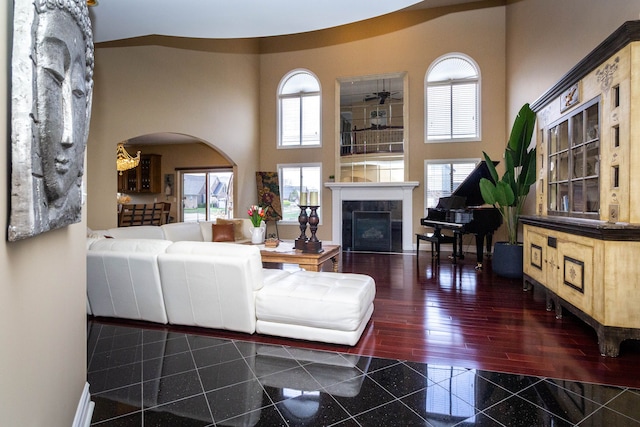 living room featuring a fireplace, granite finish floor, arched walkways, and plenty of natural light