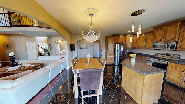 kitchen featuring arched walkways, granite finish floor, open floor plan, and appliances with stainless steel finishes