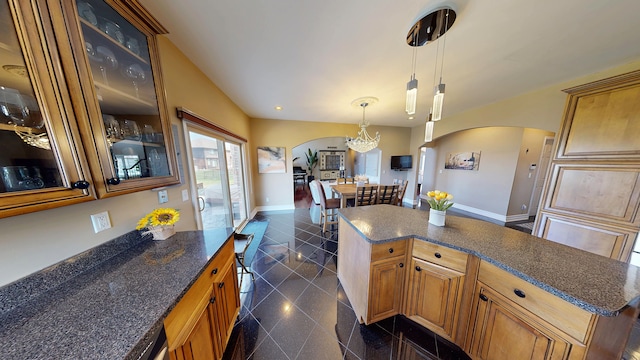 kitchen with arched walkways, glass insert cabinets, granite finish floor, baseboards, and a center island