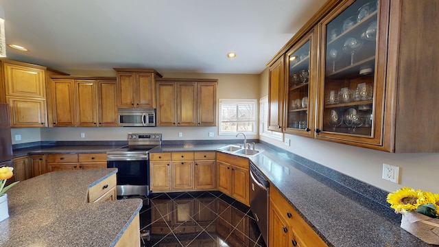 kitchen with recessed lighting, stainless steel appliances, granite finish floor, a sink, and brown cabinetry