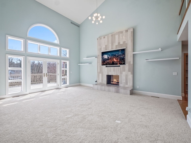 unfurnished living room with carpet flooring, a tiled fireplace, baseboards, visible vents, and high vaulted ceiling