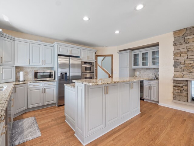 kitchen with beverage cooler, stainless steel appliances, a kitchen island, decorative backsplash, and glass insert cabinets