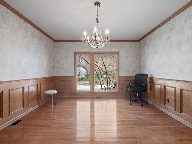 unfurnished office with wood finished floors, visible vents, a chandelier, and a wainscoted wall