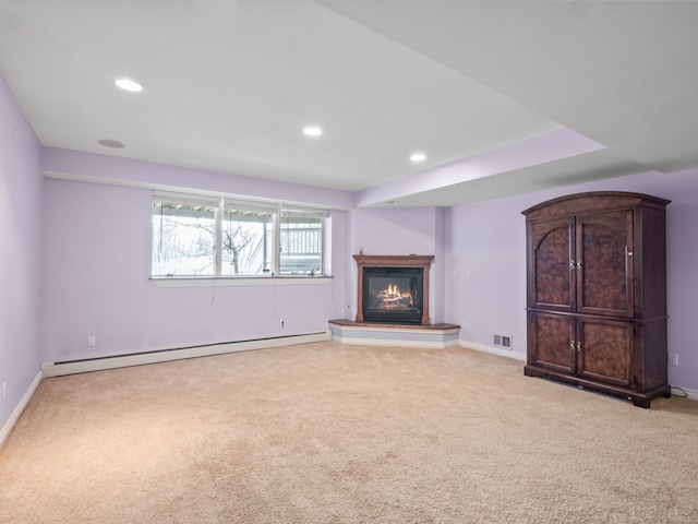 unfurnished living room featuring a baseboard heating unit, a glass covered fireplace, light colored carpet, baseboards, and visible vents