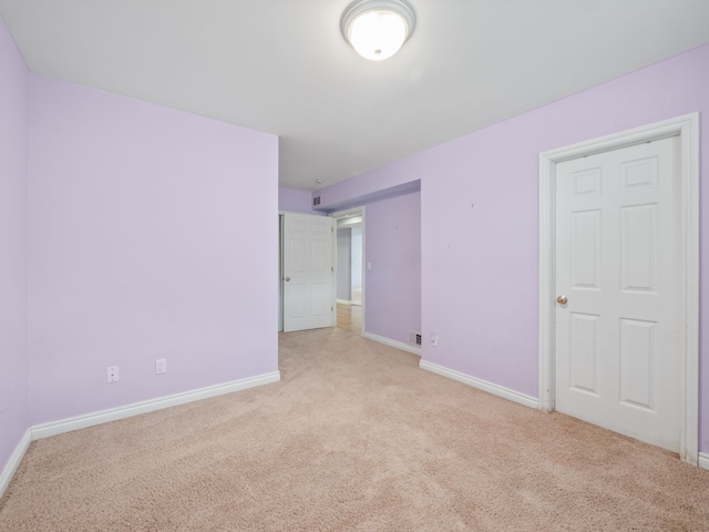 unfurnished room featuring baseboards and light carpet