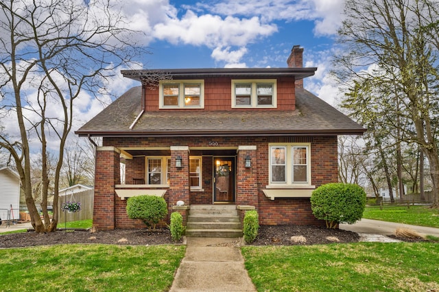 bungalow-style home with brick siding, a front lawn, and covered porch