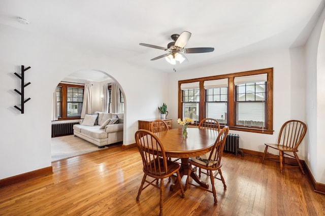 dining area with arched walkways, radiator heating unit, a wealth of natural light, and baseboards
