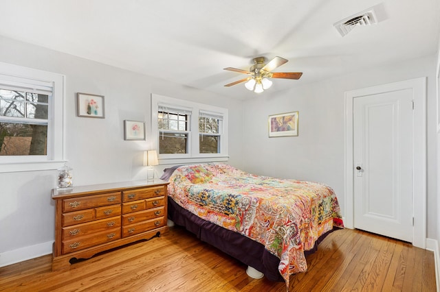 bedroom with light wood-style floors, ceiling fan, visible vents, and multiple windows