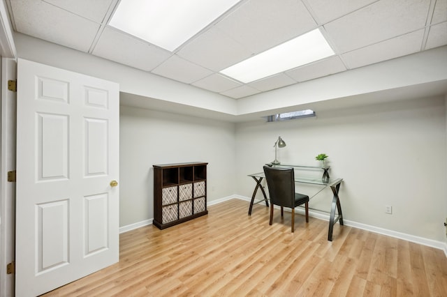 office area featuring light wood-type flooring, baseboards, and a drop ceiling