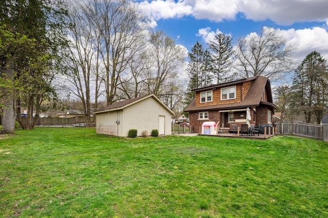 rear view of property with a lawn, a shingled roof, a fenced backyard, an outbuilding, and brick siding