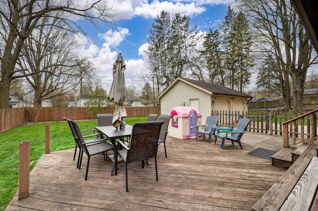 deck with a fenced backyard, an outdoor structure, a yard, and outdoor dining area