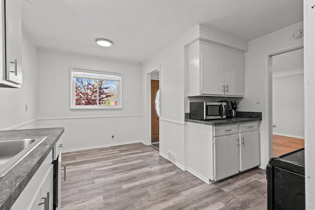 kitchen with visible vents, dark countertops, stainless steel microwave, light wood-style floors, and black range with electric cooktop
