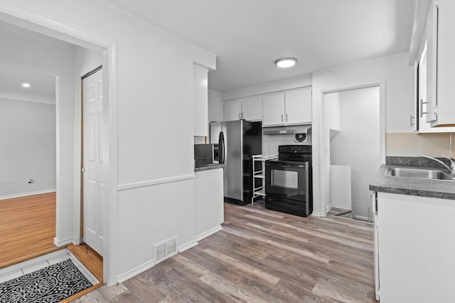 kitchen with visible vents, black electric range oven, stainless steel fridge, a sink, and light wood finished floors