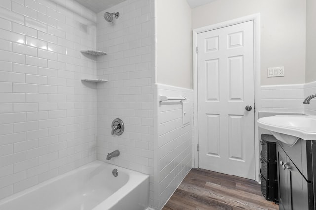 bathroom with vanity, washtub / shower combination, wood finished floors, and a wainscoted wall