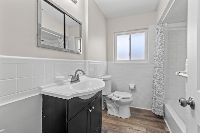 full bath featuring vanity, wainscoting, wood finished floors, toilet, and tile walls