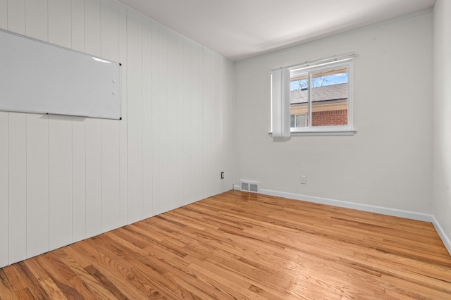 unfurnished room with baseboards, visible vents, and wood finished floors