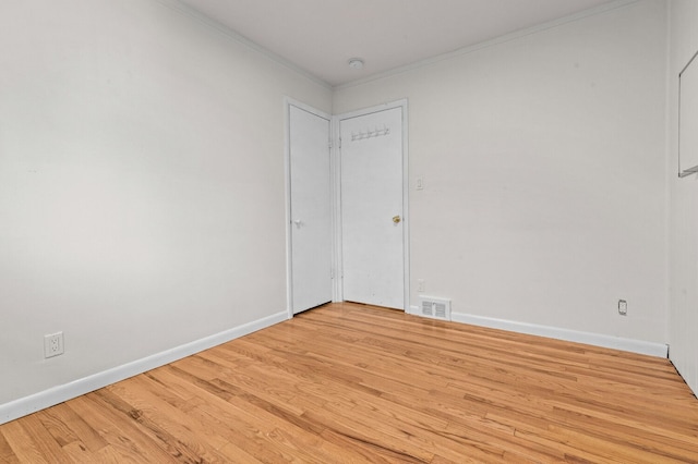unfurnished room with baseboards, ornamental molding, light wood-style flooring, and visible vents