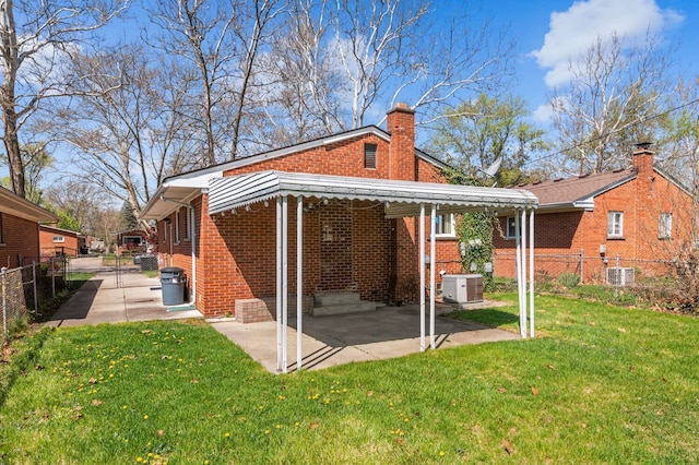 back of property with brick siding, a fenced backyard, a yard, and a chimney