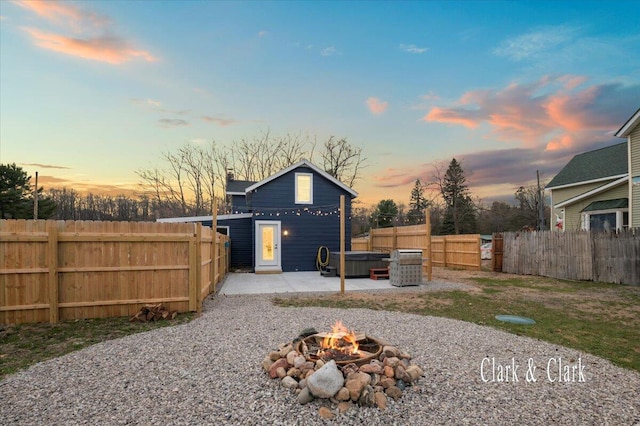 exterior space with a fire pit, a fenced backyard, a hot tub, and a patio