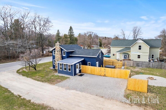 view of front of property featuring fence, gravel driveway, and a chimney