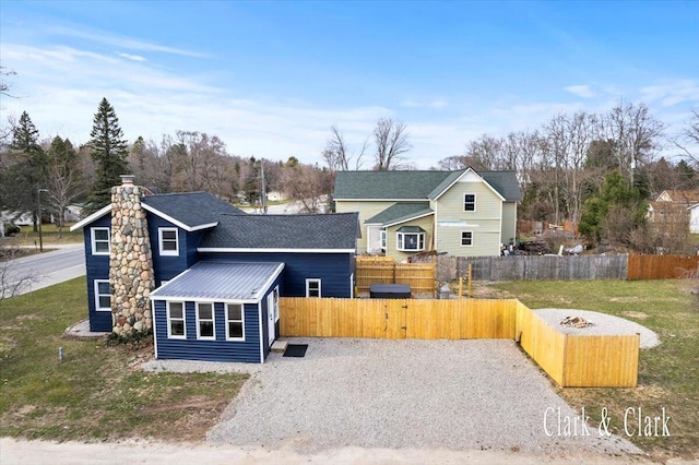 view of front of property featuring a front lawn, a gate, driveway, a chimney, and fence
