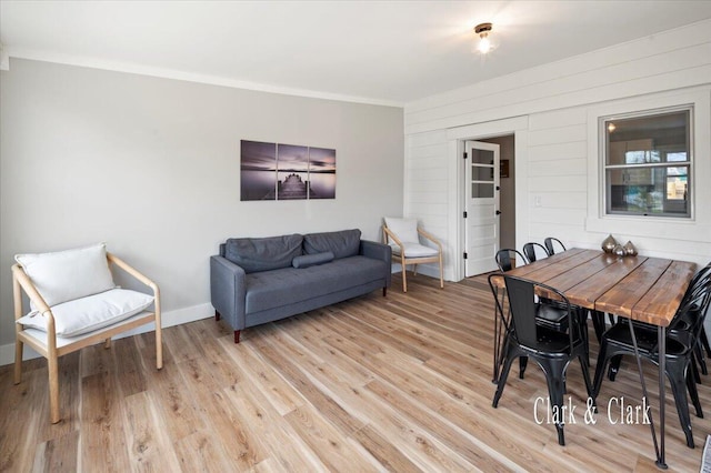 dining area featuring light wood-style flooring, baseboards, and ornamental molding