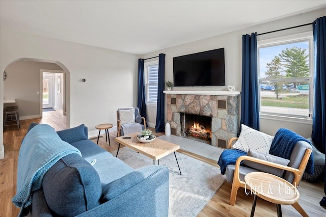 living area featuring arched walkways, a wealth of natural light, baseboards, and a fireplace