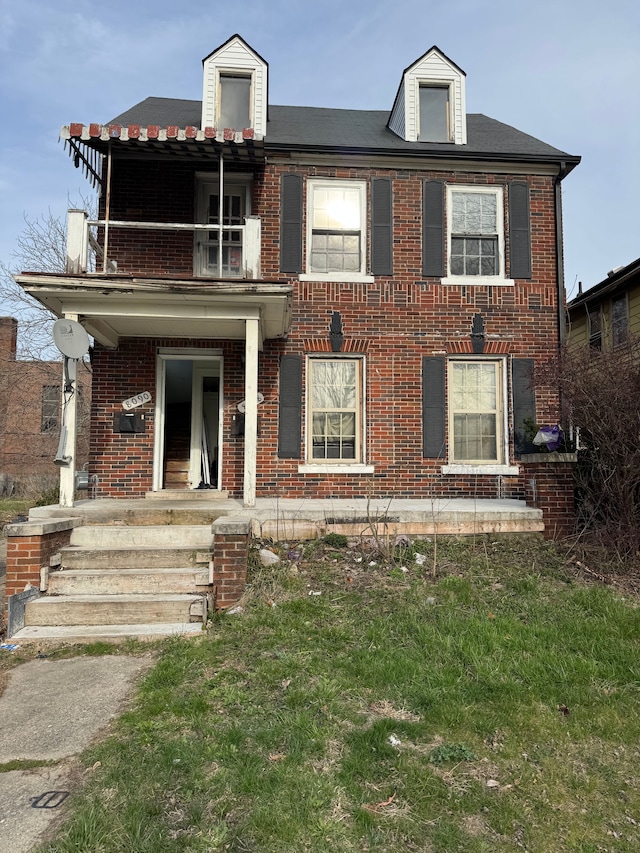 view of front of house featuring brick siding and a balcony