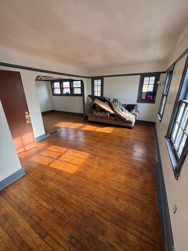 unfurnished living room featuring a textured ceiling, hardwood / wood-style flooring, and a wealth of natural light