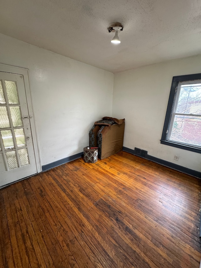 unfurnished room featuring hardwood / wood-style flooring, baseboards, and a textured ceiling