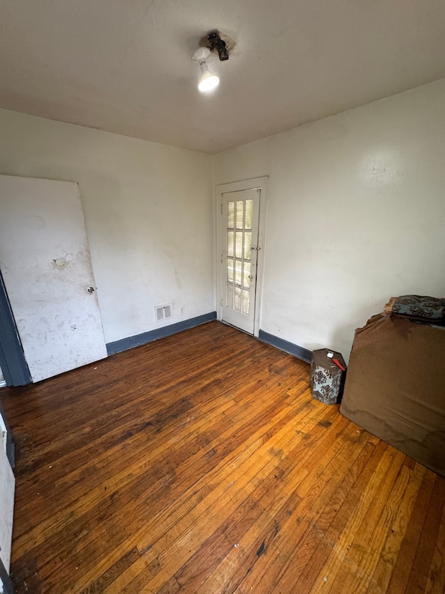 unfurnished room featuring wood-type flooring, visible vents, and baseboards
