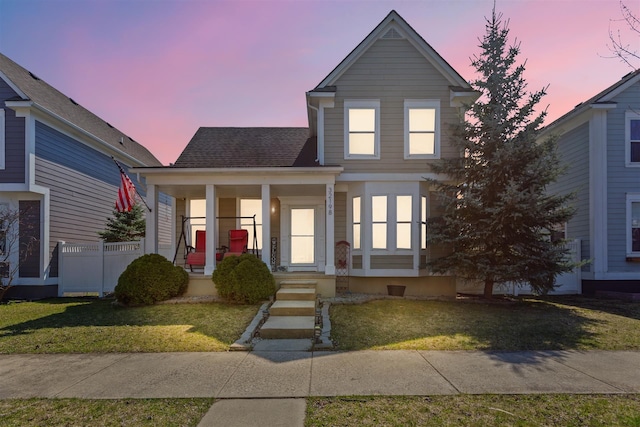 traditional home featuring a porch, a front lawn, and a shingled roof
