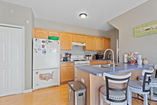 kitchen featuring a kitchen breakfast bar, a sink, white appliances, a peninsula, and under cabinet range hood